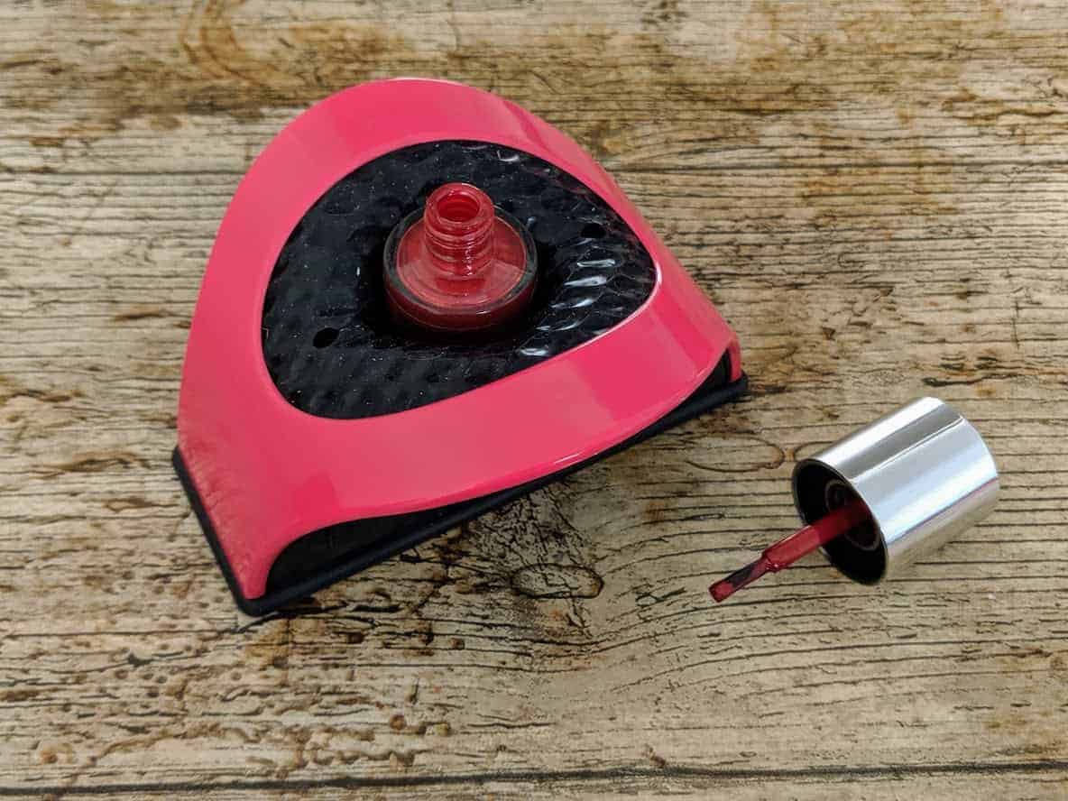 Nail buddy with nail polish bottle in and brush next to it