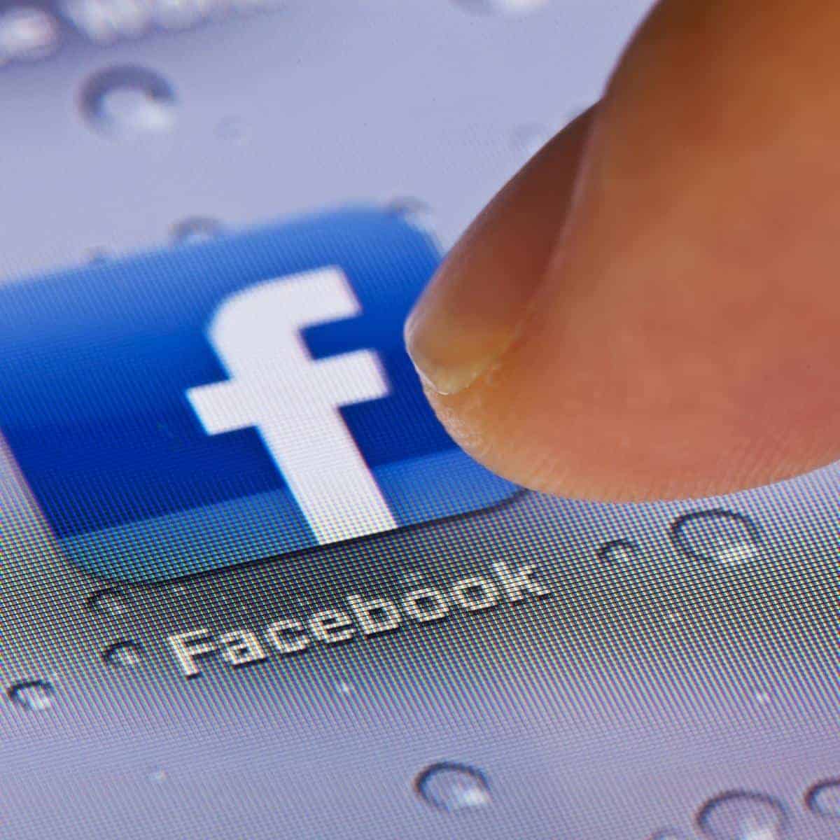 finger pressing facebook icon on a phone or tablet