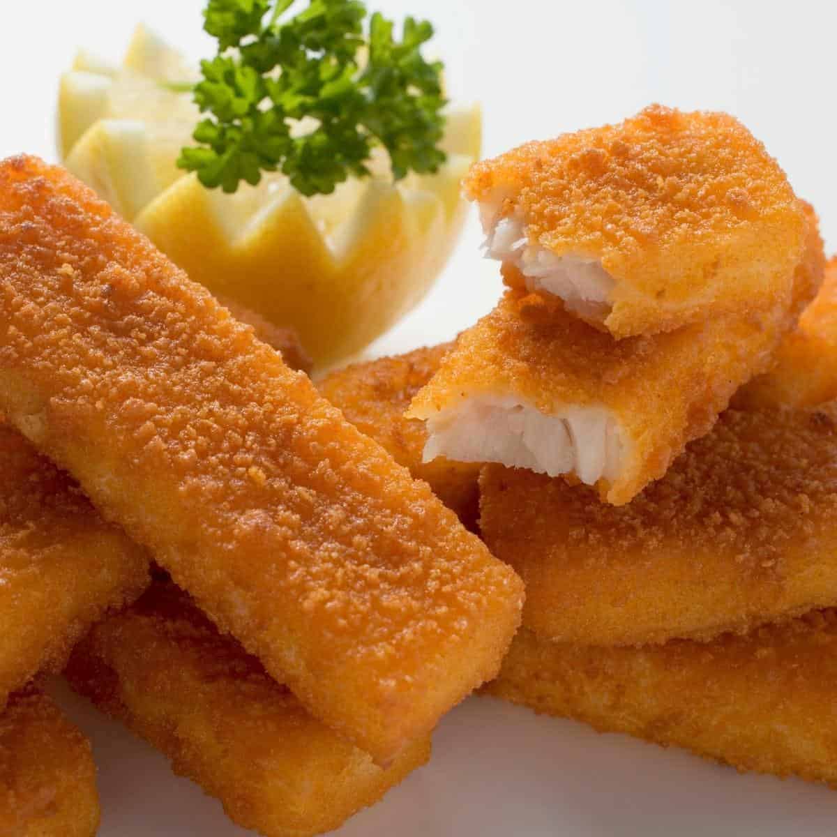 Fish fingers piled on a plate.