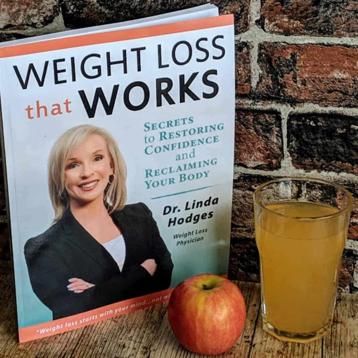 Dr Linda hodges book with glass of squash and an apple