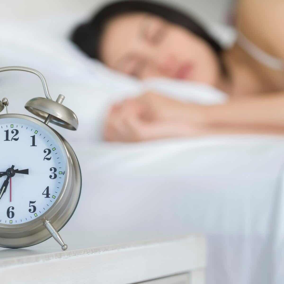 alarm clock with lady asleep in background