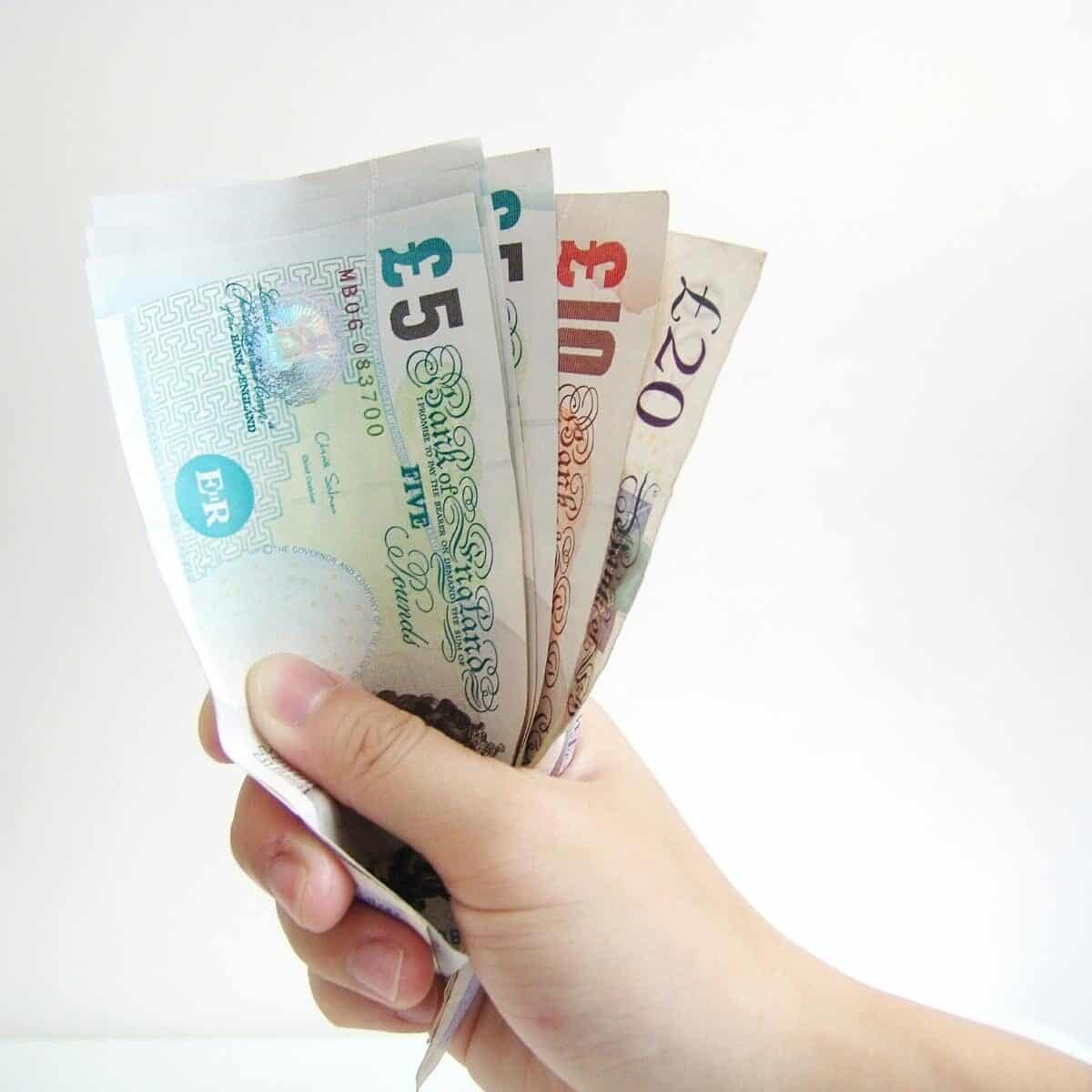 Uk money fanned out in a hand over a white background