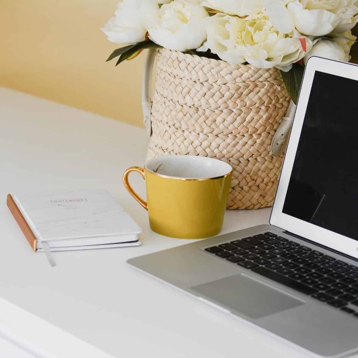 working from home coffee notebook, flowers and laptop