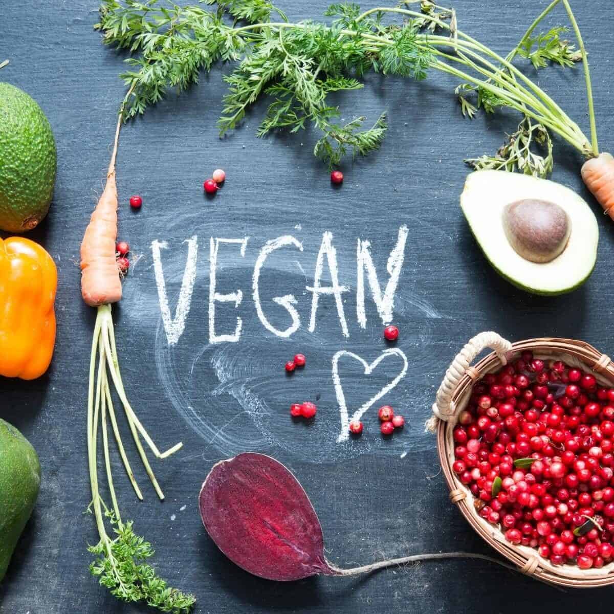 vegan written on a blackboard surrounded by vegan foods
