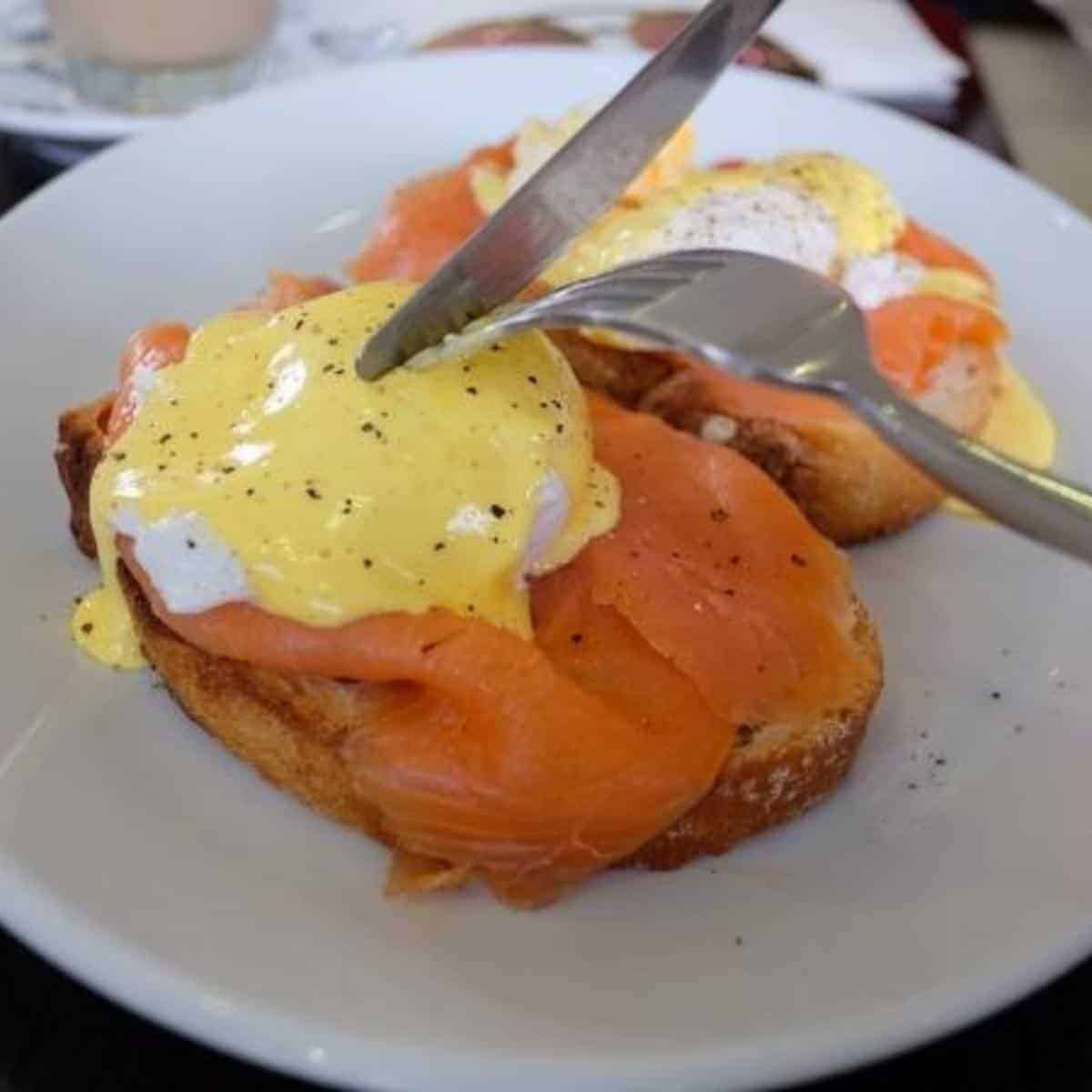 Cutlery cutting into Eggs Royale on a white plate