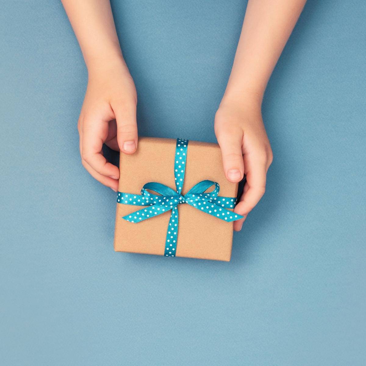 hands handing a gift over a blue background