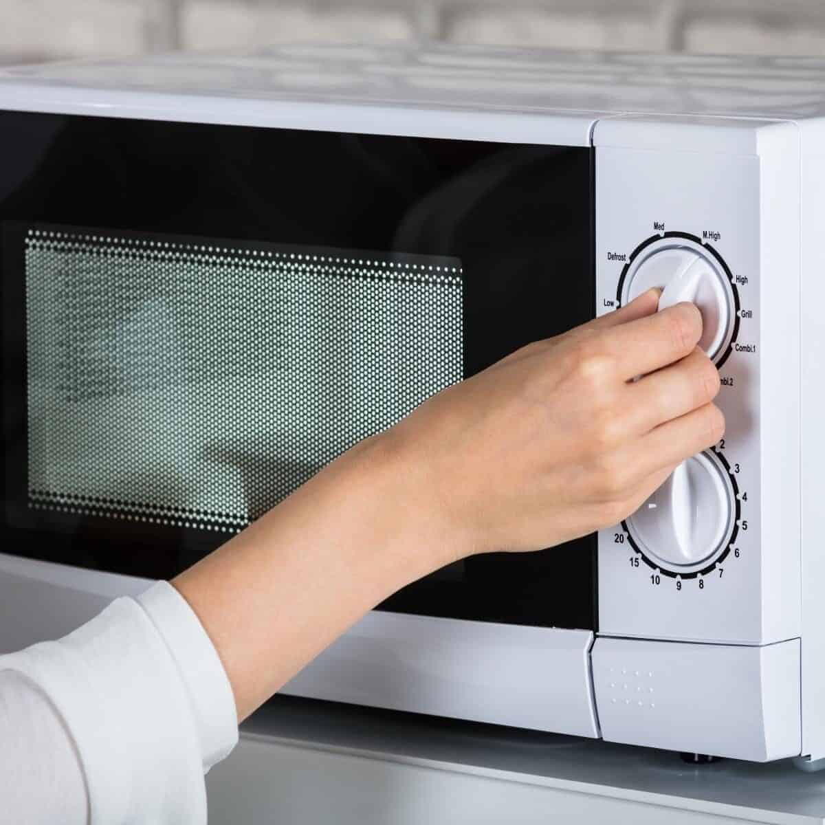 microwave with ladies hand turning the dial