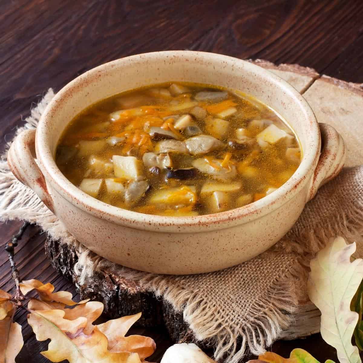 A bowl of mushroom soup sitting on top of a wooden table