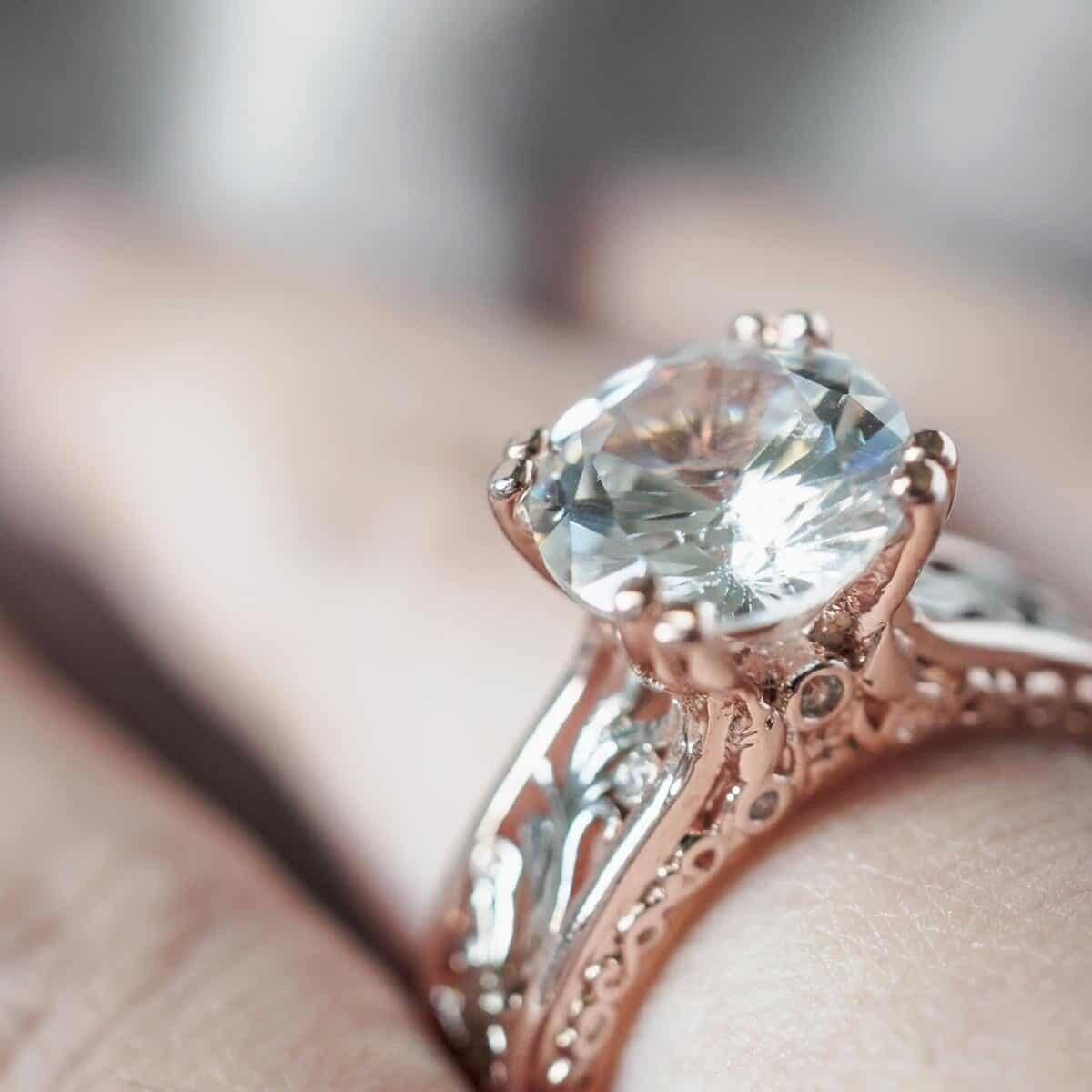 Diamond ring on a finger with a large solitaire diamond and diamonds on the ring shoulders too.