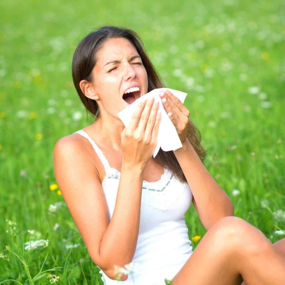 sneezing lady on grass with hay fever