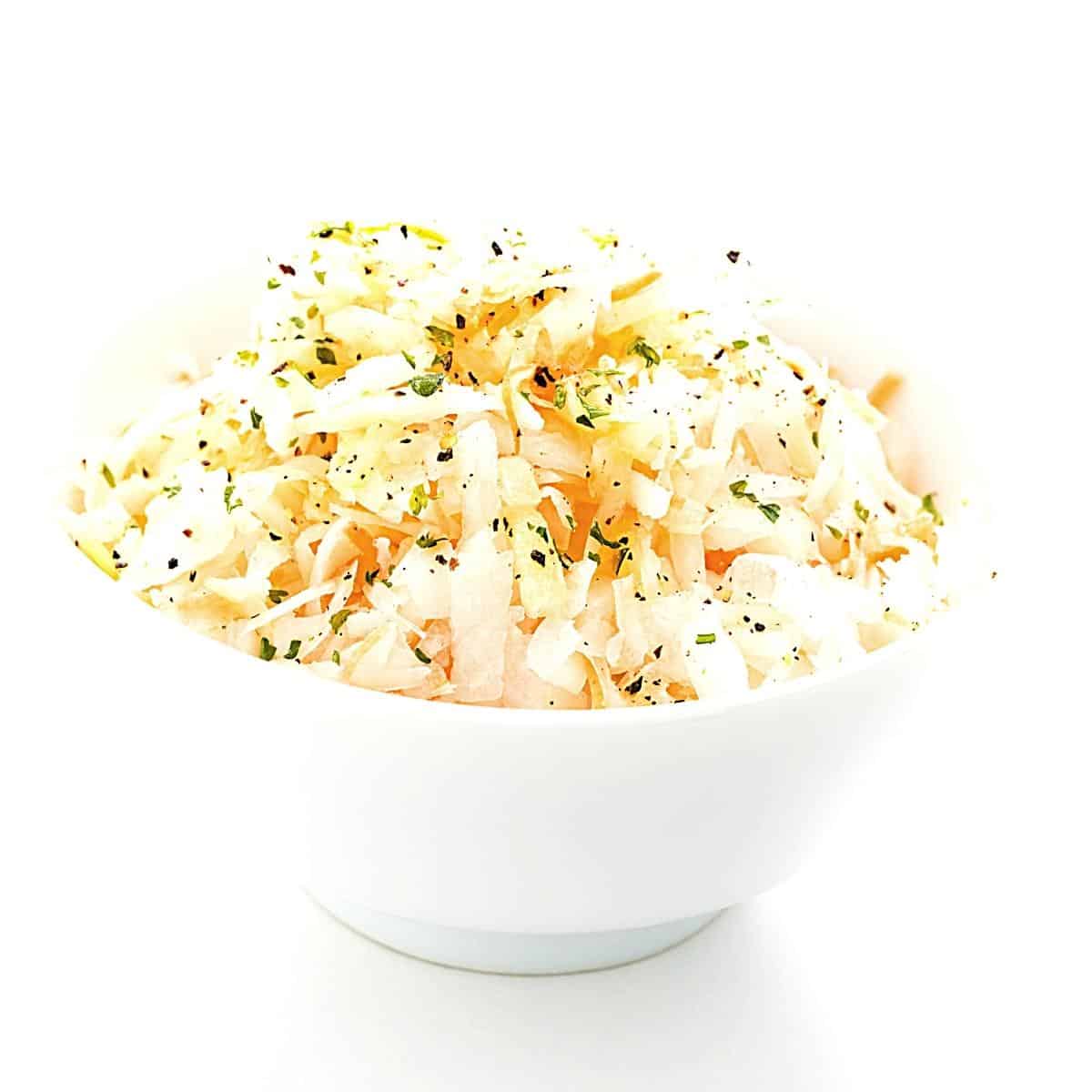white bowl of coleslaw topped with freshly cracked black pepper