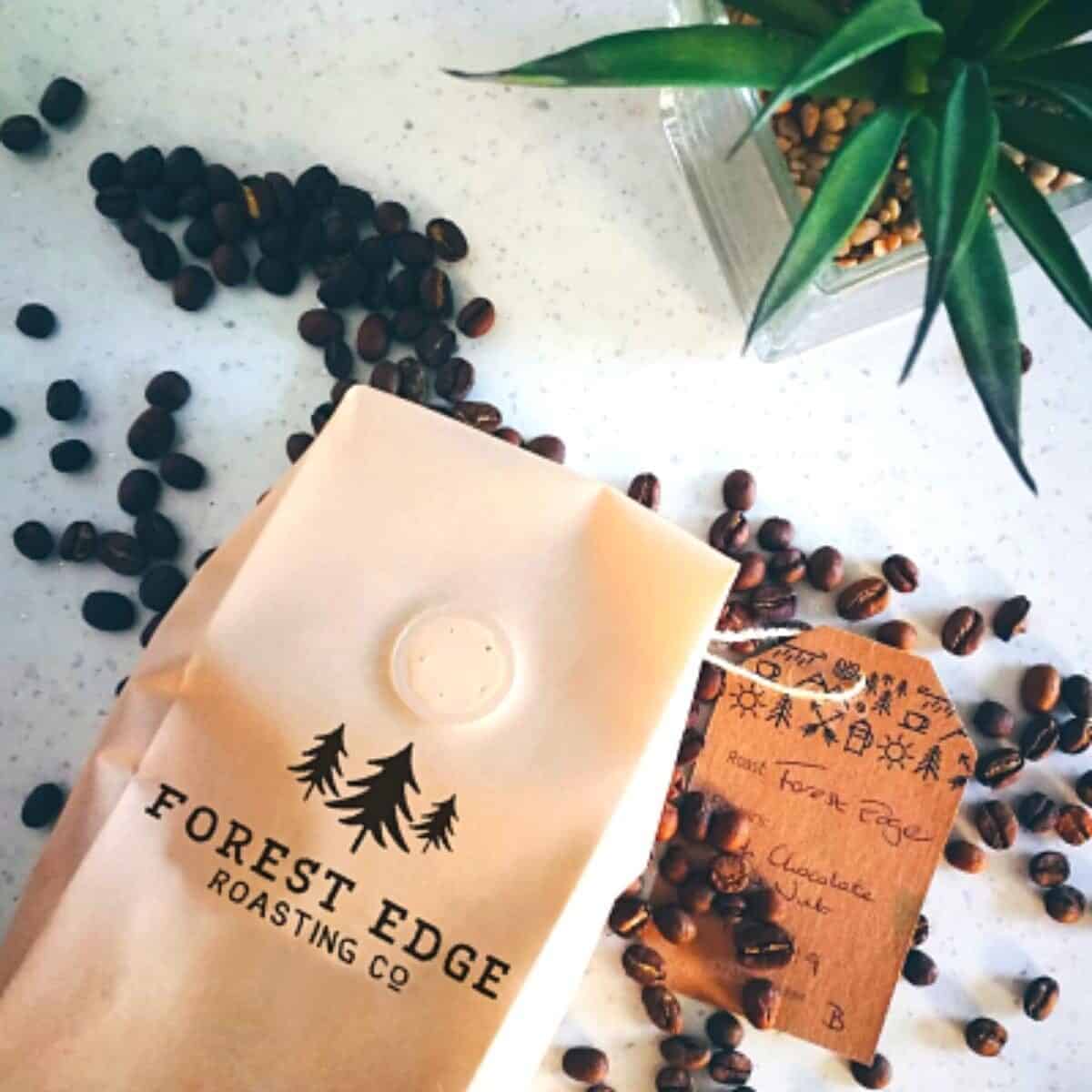 brown bag of coffee beans with some spilled out on a white table.