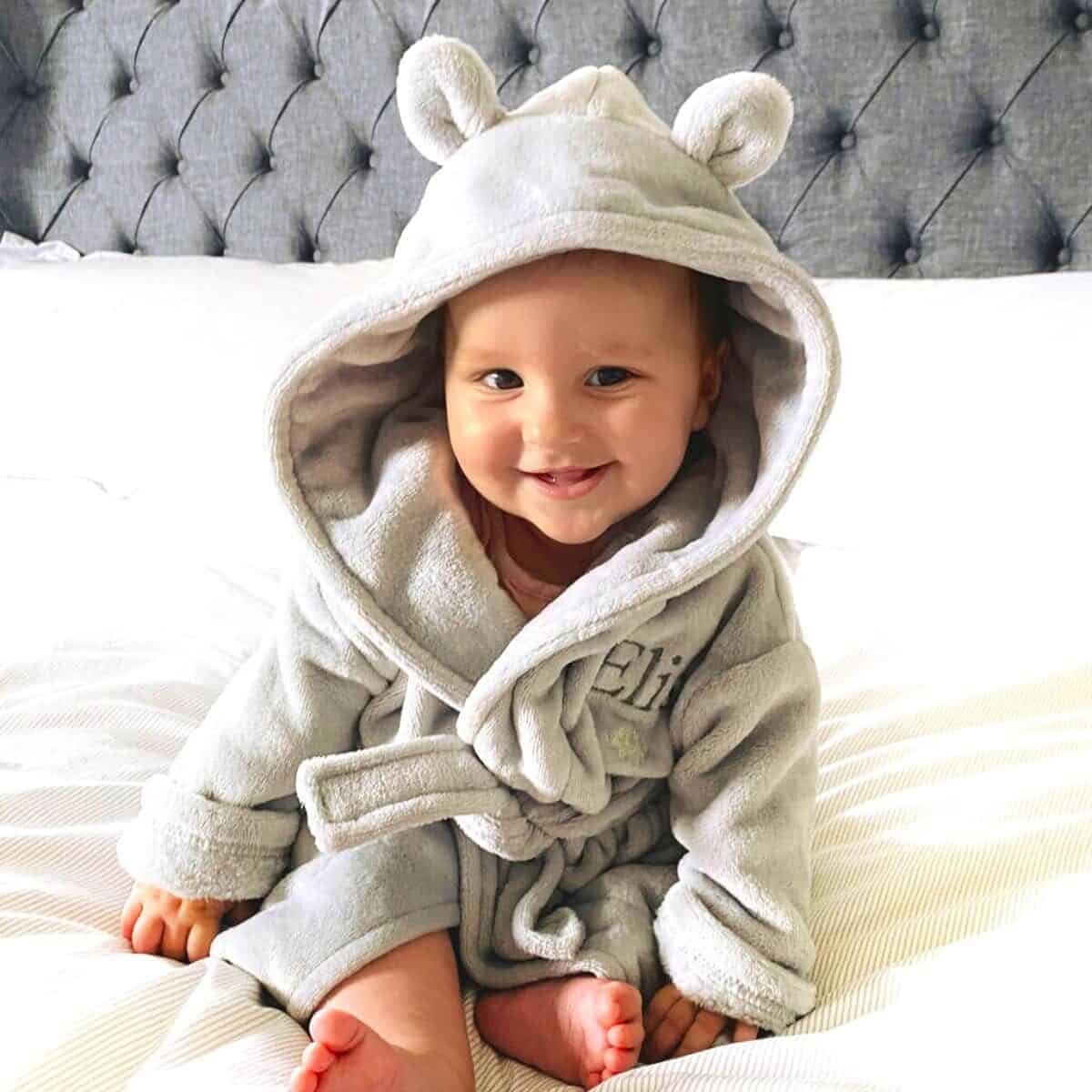 a baby wearing a hoodie on a bed