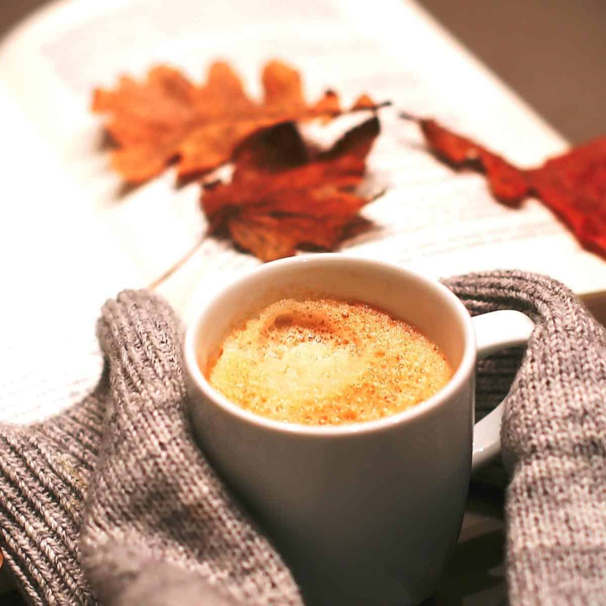 autumn leaves and jumper holding hot drink