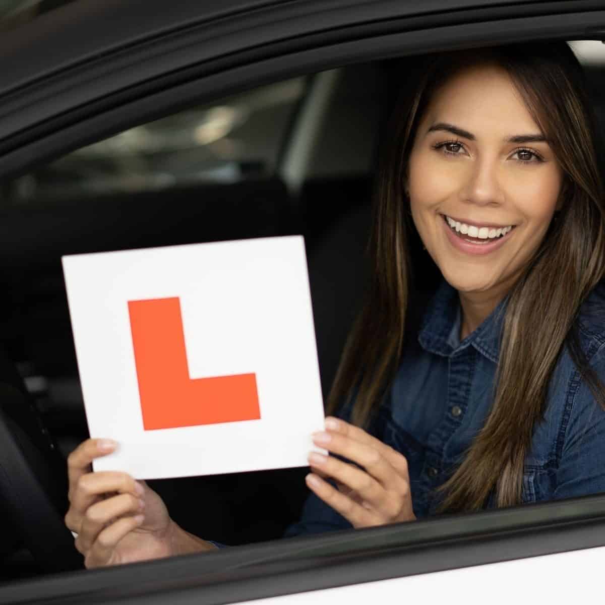 lady holding l plate in a car