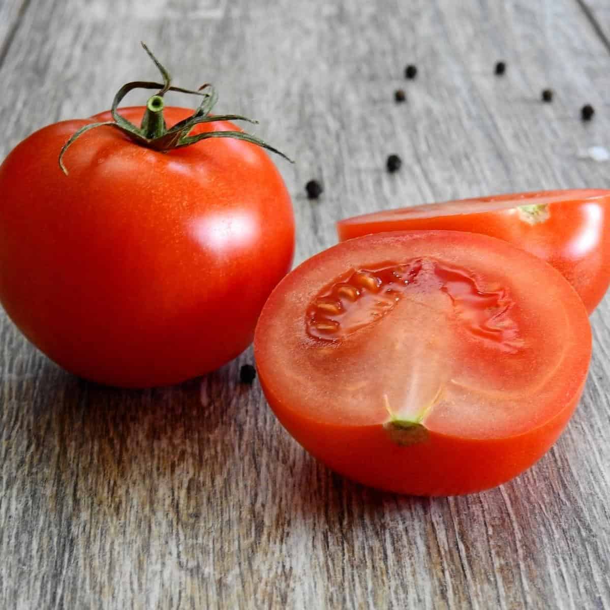Tomato sliced in half on a wooden board.