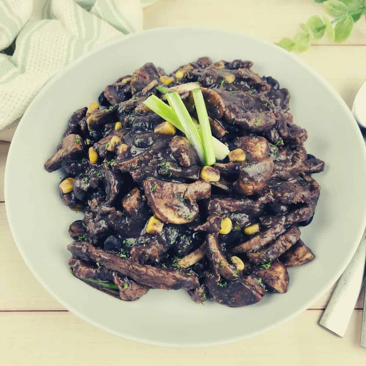 beef in black bean sauce in a white bowl