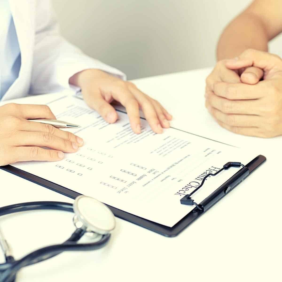 doctor with clipboard and stethoscope on a desk.