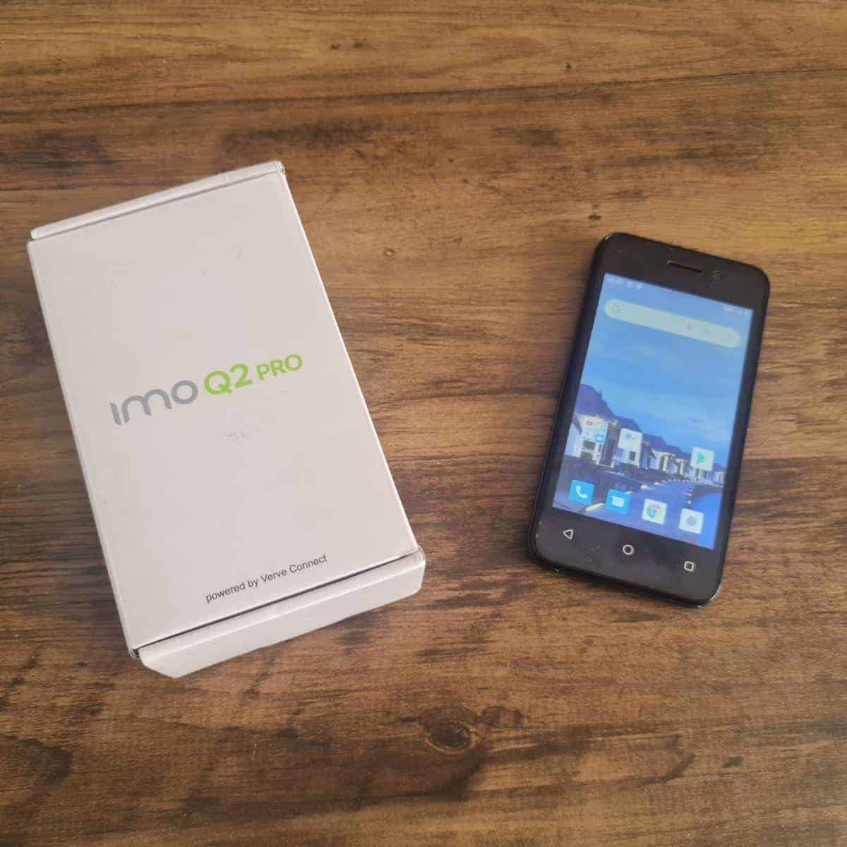The sleek IMO Q2 Pro smartphone rests elegantly on a wooden surface, perfectly paired with its stylish box.