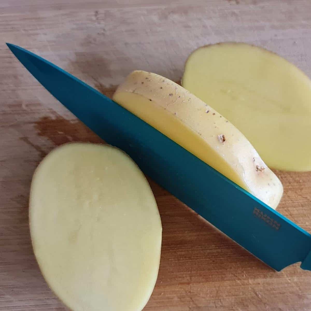 knife cutting potatoes on wooden board