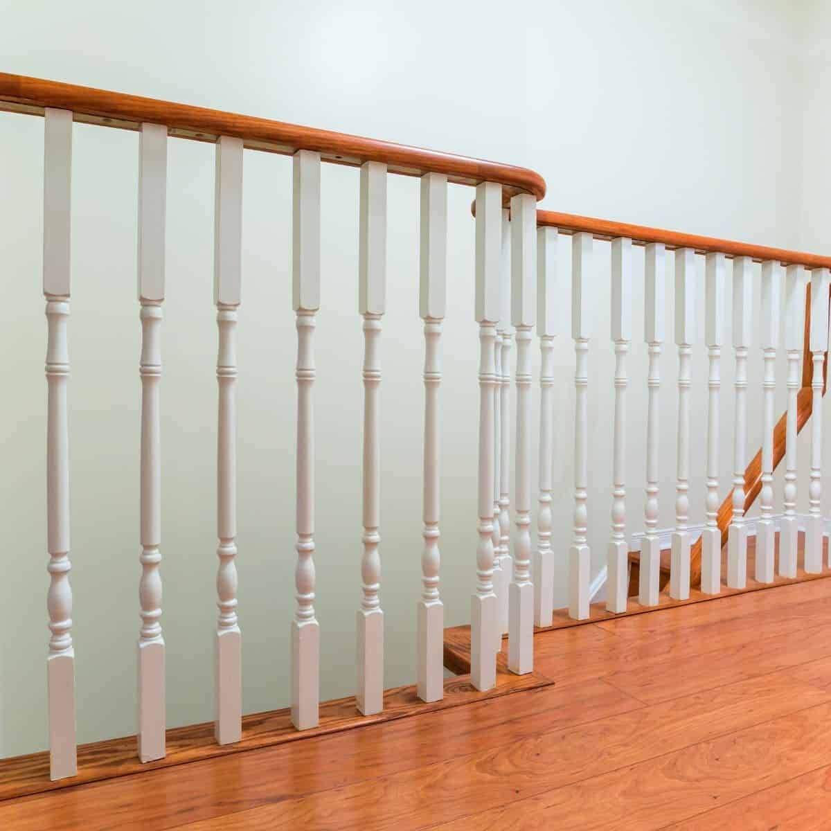 Wooden floor with white spindles and a wooden top at the top of a staircase.