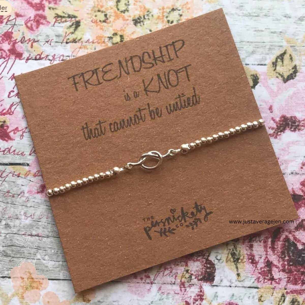 A silver bracelet on a card with the words \"friendship is a knot that cannot be untied\".