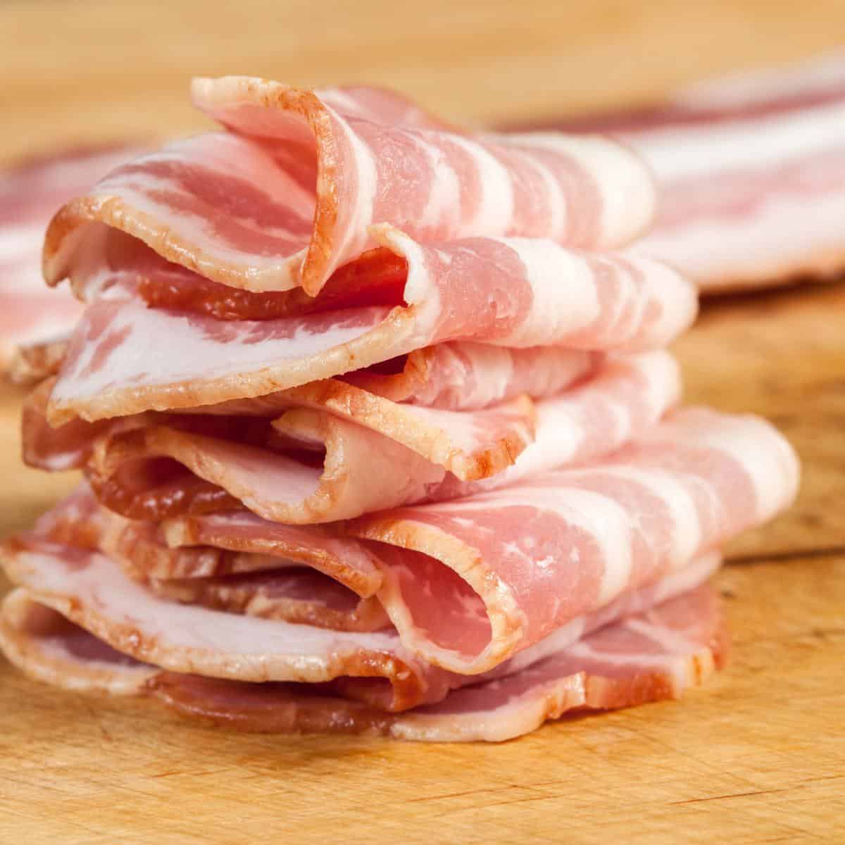 bacon rashers folded and stacked on a chopping board.