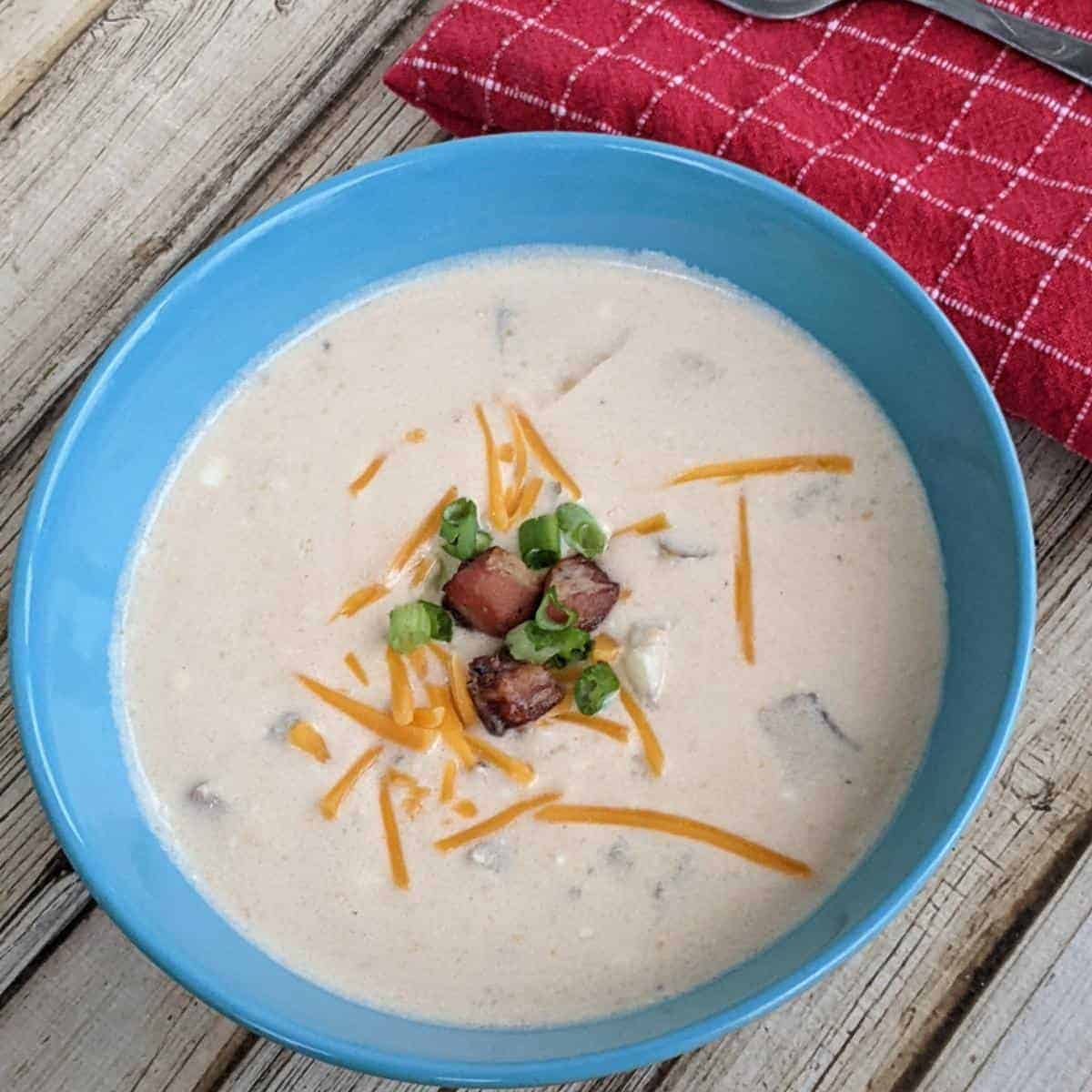 Bowl of baked potato soup from the instant pot in a blue bowl on a wooden table.