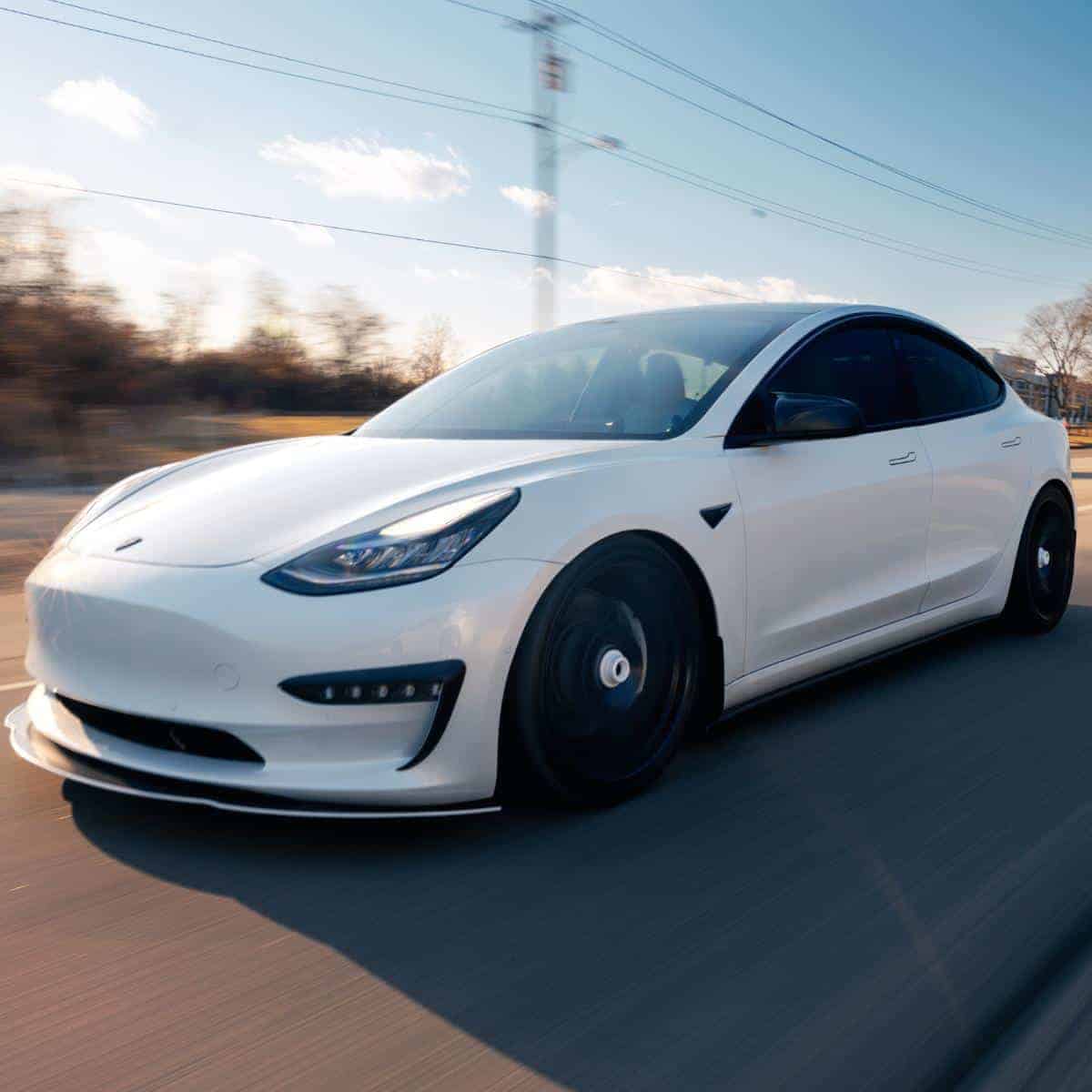 A white tesla car on a road.
