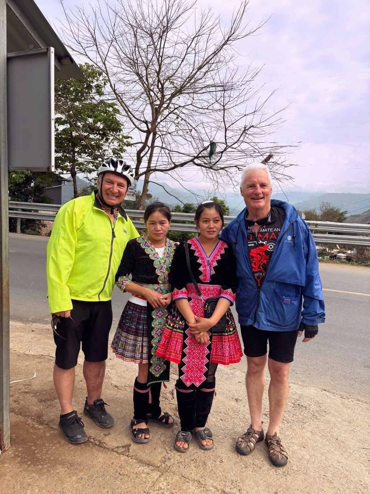 Cyclists enjoying a Laos countryside cycling experience along quiet rural roads, passing traditional villages, green valleys, and scenic mountain landscapes near Luang Prabang.
