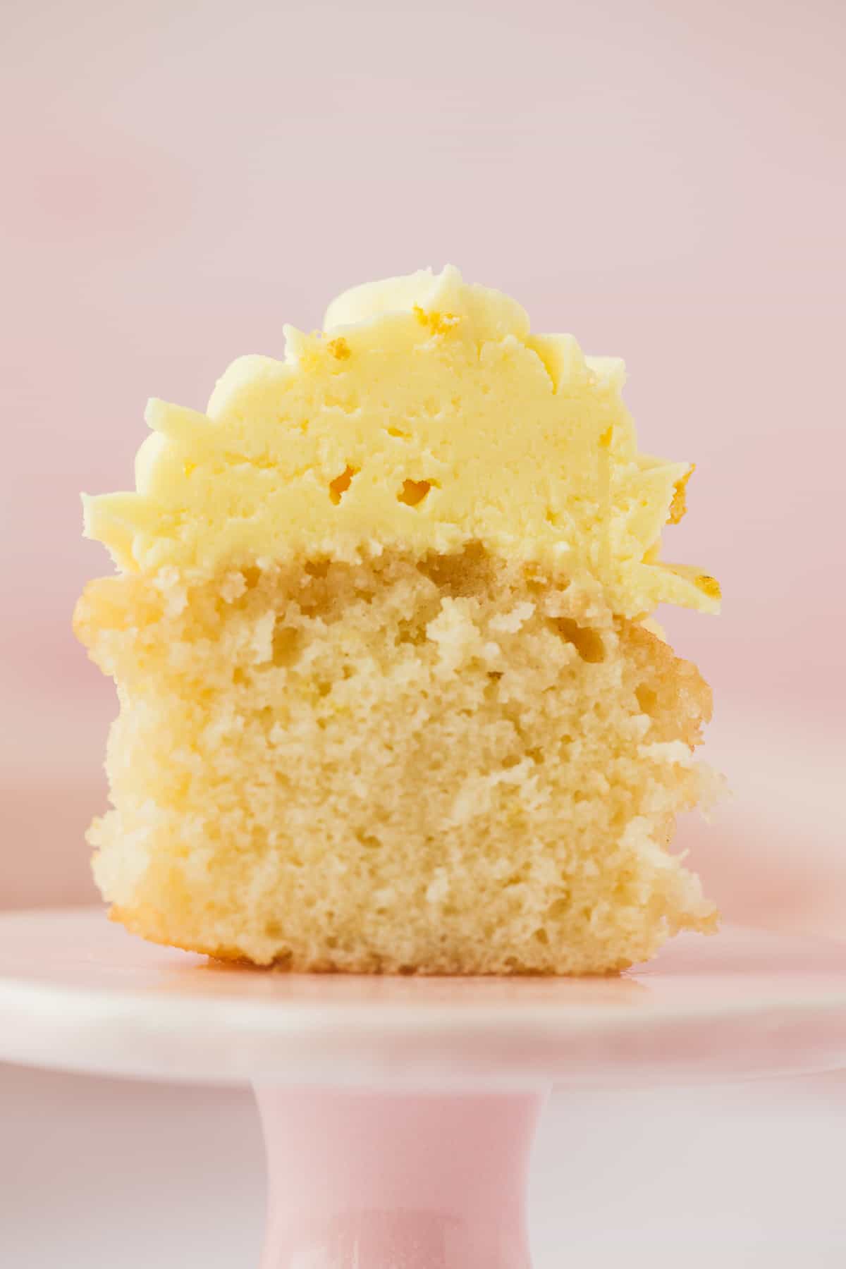 A lemon drizzle cupcake that has been sliced open to reveal it's soft moist centre.