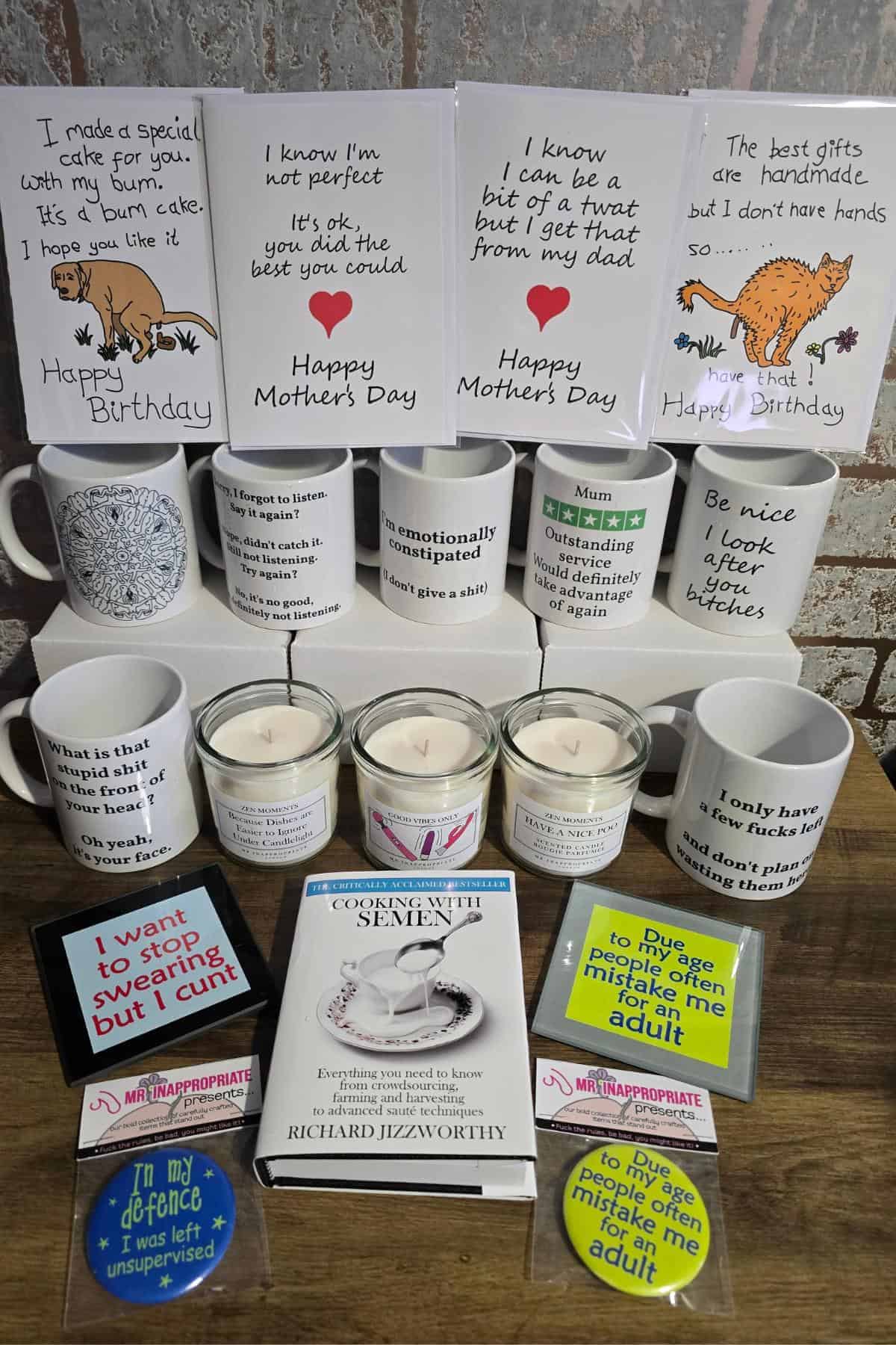 A display of humorous cards, mugs, candles, coasters, and a book. Featuring Mr Inappropriate Review-level cheeky messages for birthdays and Mother’s Day, witty candle labels, funny coaster phrases, and the book "Common Sense Isn’t.