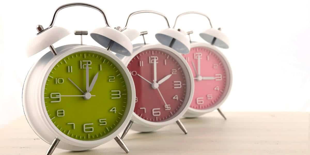 3 analog clocks, one green, one pink, one mauve with white trim. Showing daylight savings.