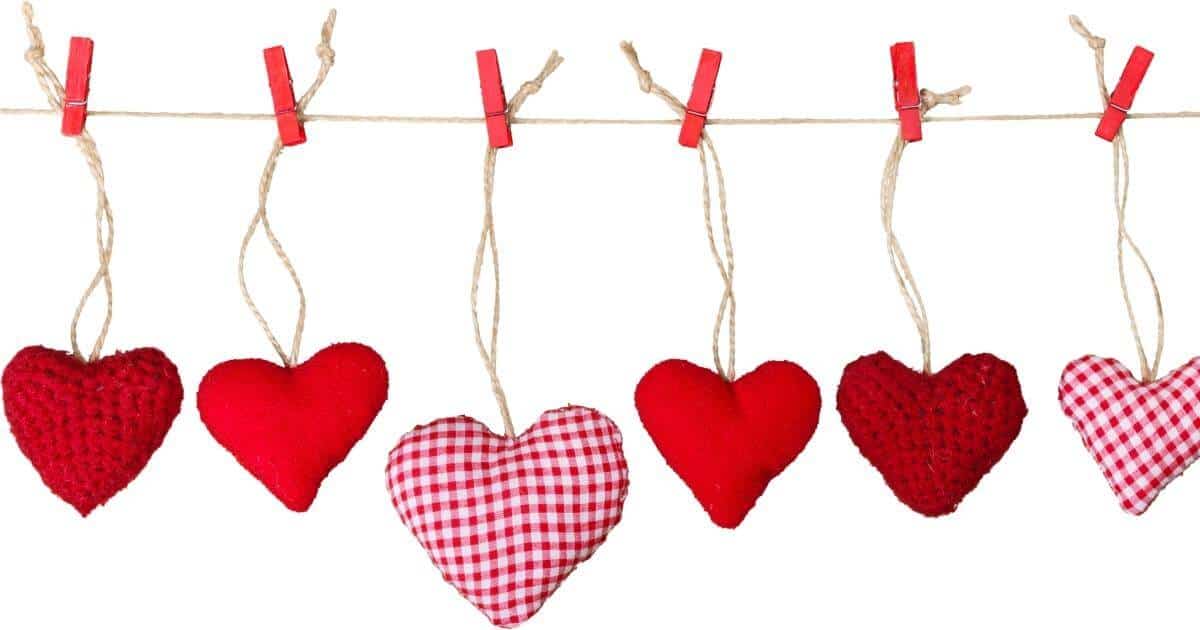 red stuffed hearts on strings clothes pinned to a clothesline