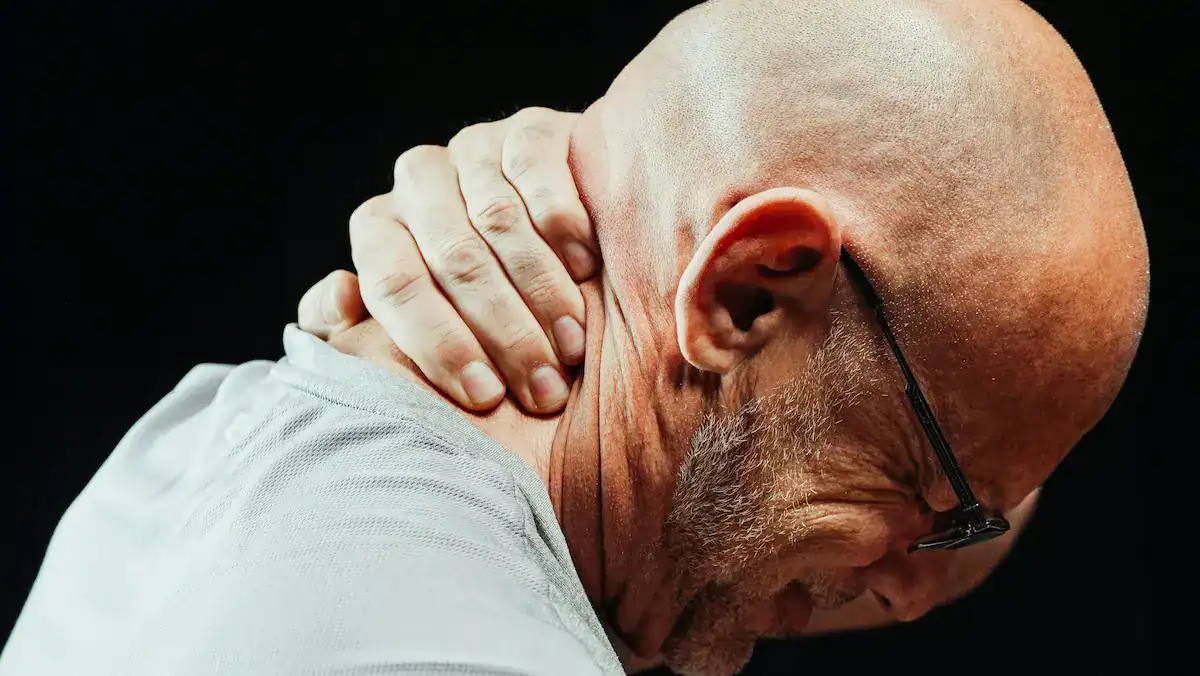 someone with neck pain holding their neck
