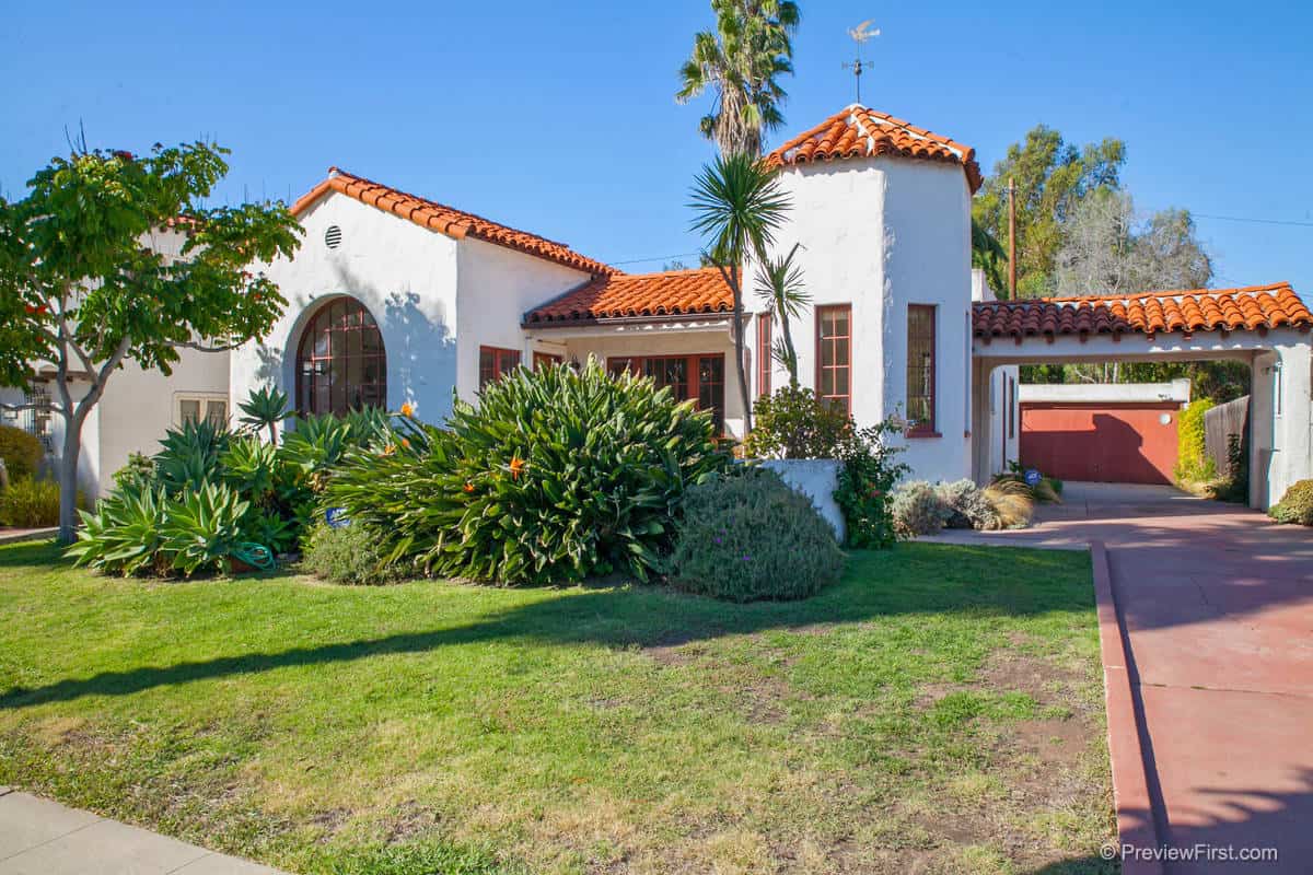 Historic Spanish-style home at 2124 Upas Street in North Park, featuring white stucco walls, a red clay tile roof, a distinctive turret, and lush desert landscaping.