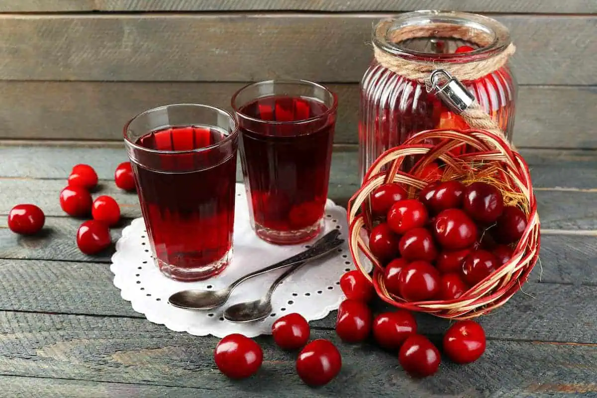 glasses of cherry kompot next to fresh cherries.