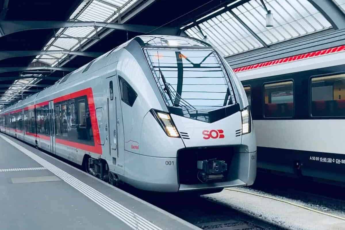 A grey and red train pulls into a train station alongside a white double-decker train carriage. YouTube is a great way of learning how to navigate an airport or train station before setting off on your travels.