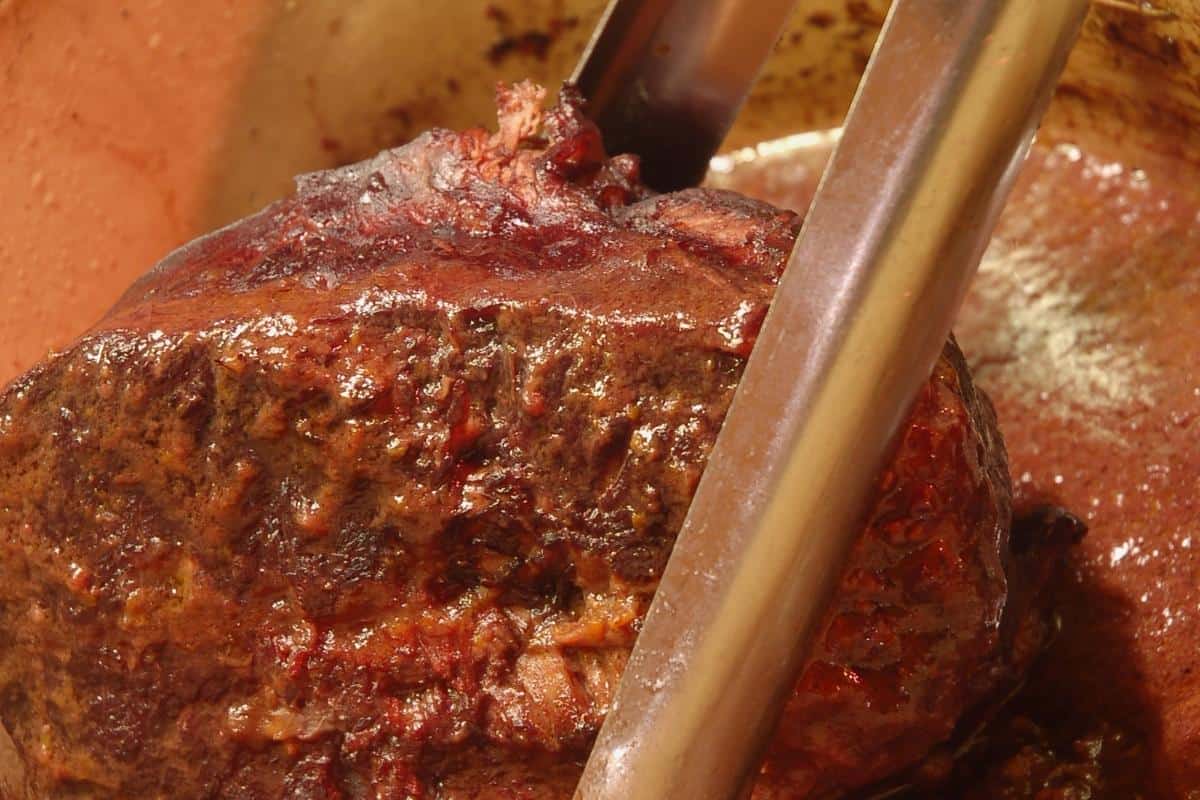 beef in red wine being removed from slow cooker with metal tongs