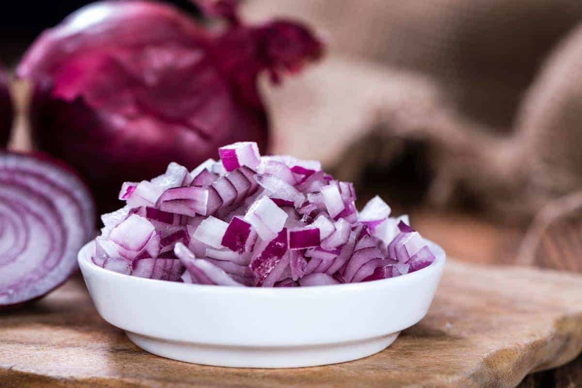 Diced red onions in a small white bowl.