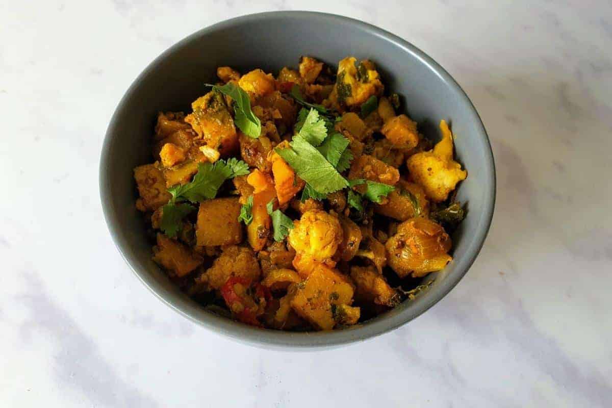 Aloo Gobi cooked and served in a grey bowl sprinkled with chopped coriander.