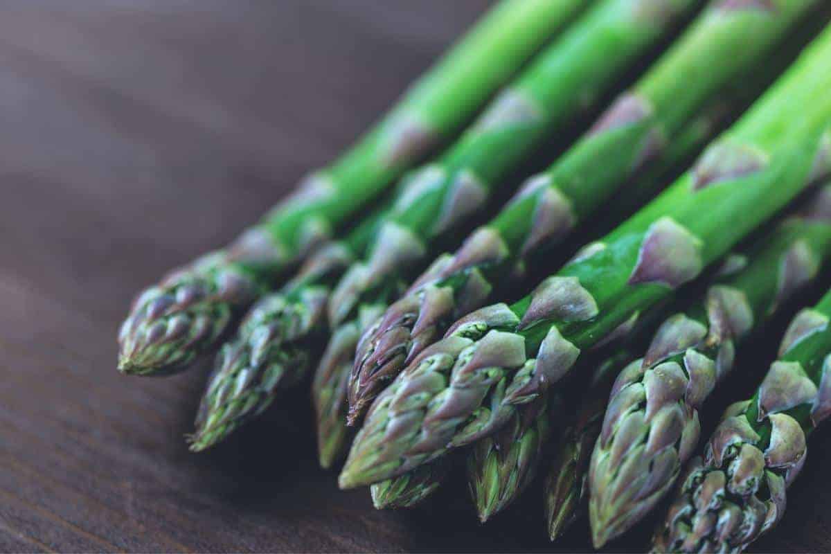 bunch of asparagus on dark wooden board