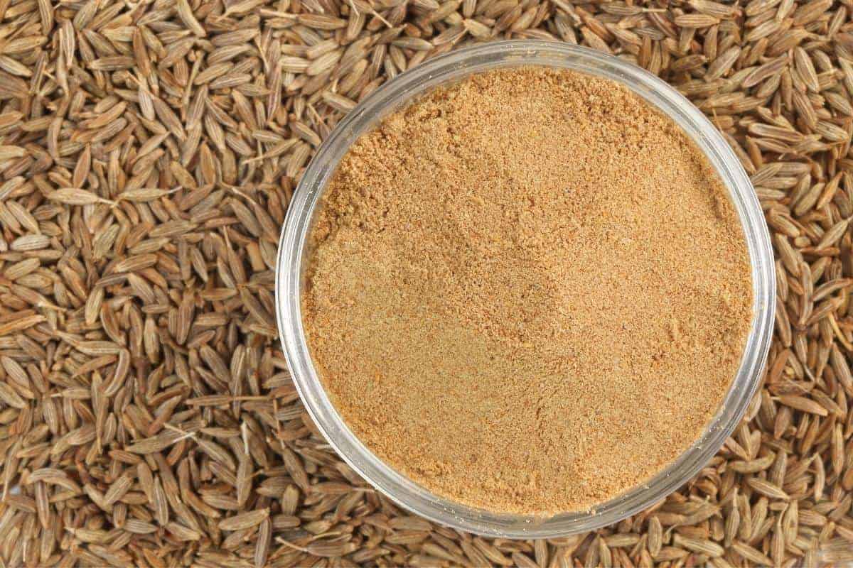 Cumin seeds with a bowl of ground cumin in the middle