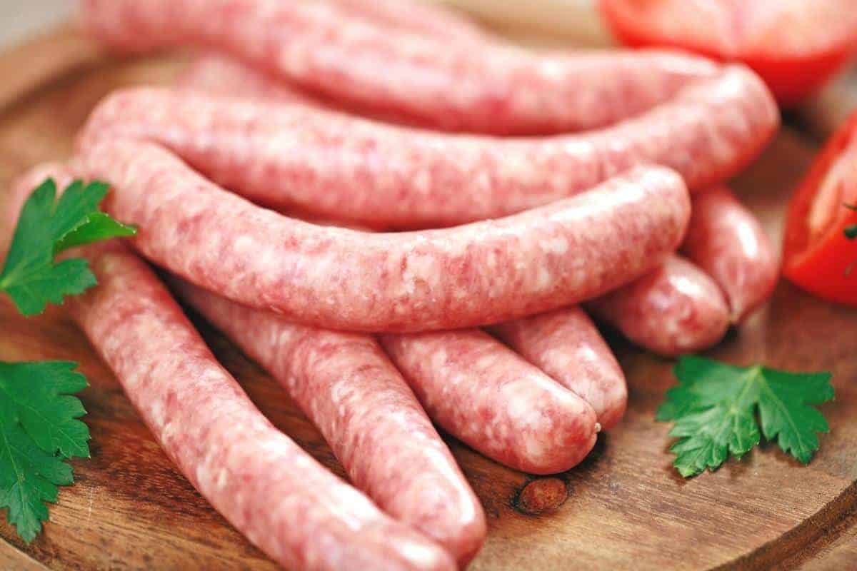 raw sausages on a wooden board.