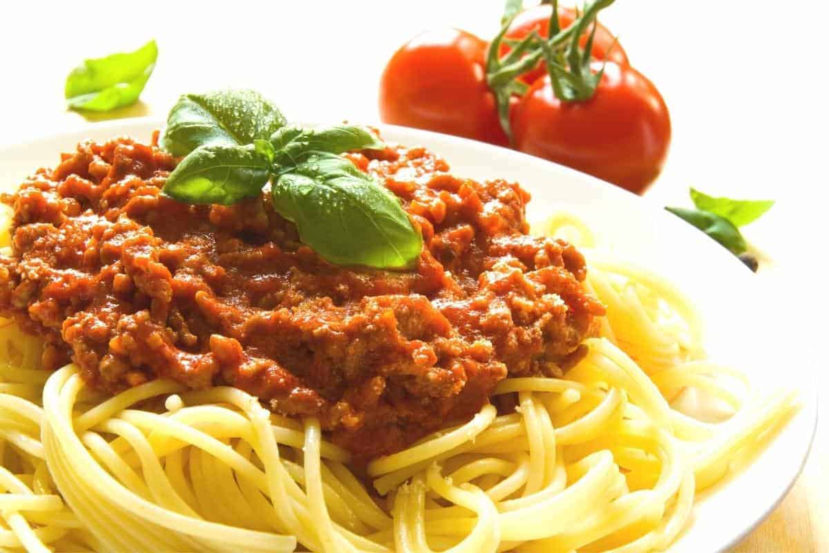 Spaghetti Bolognese in a bowl topped with a sprig of basil.