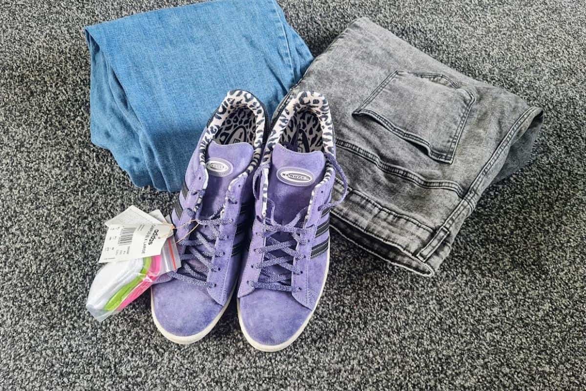 Two pairs of jeans and some purple adidas trainers.