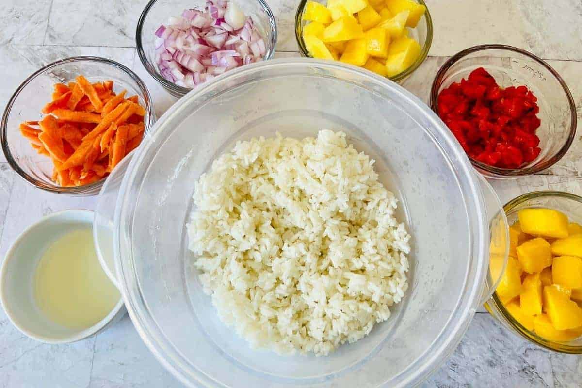 bowl of cooked rice with small bowls of all the ingredients needed for Caribbean rice.