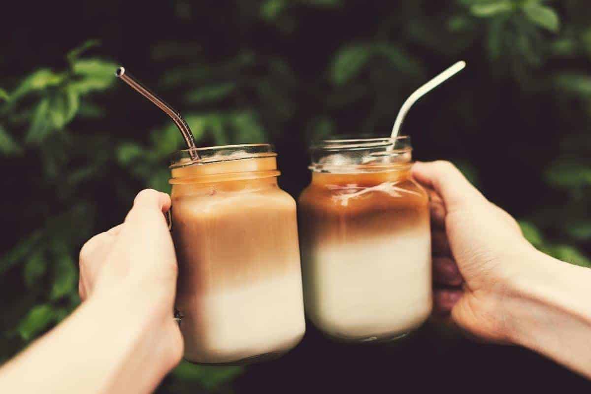 two hands holding jars with drinks