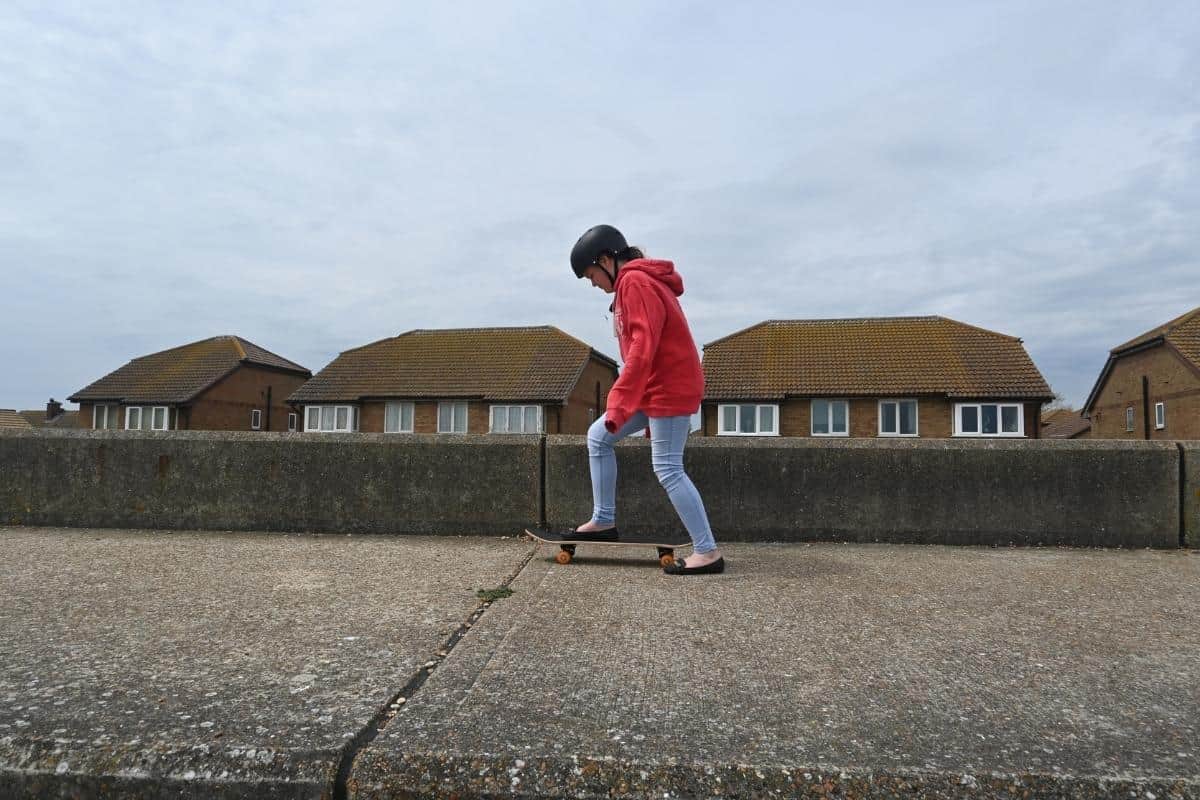 teenage girl skateboarding on concrete on the beach front.