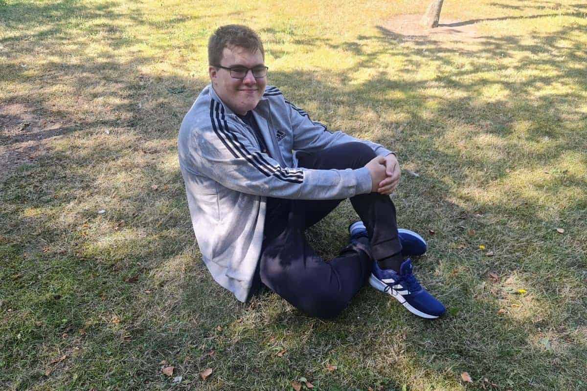 Teenage boy sitting on the grass in adidas clothes